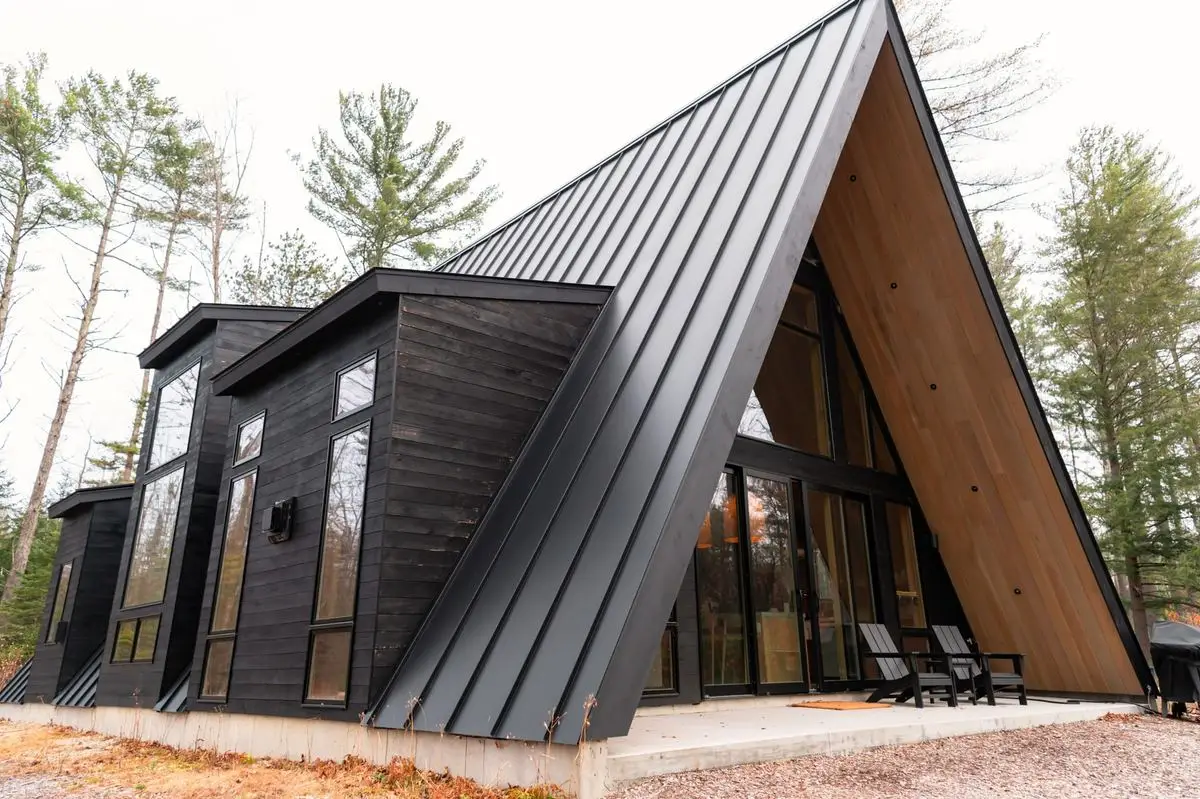 Steep dark metal roof on a timber-clad house